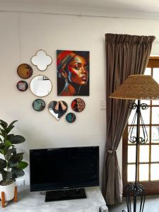 a living room with a tv and a painting on the wall at The Keep Cottage in Underberg
