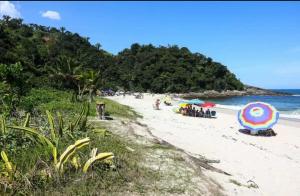 a beach with a group of people and umbrellas at Refúgio Aconchegante in São Sebastião