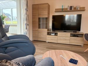 a living room with a tv and a blue chair at Ferienhaus Edda in Timmendorfer Strand