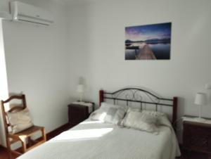 a bedroom with a bed and a chair at Casa Rebelo in Cossourado