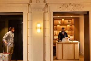 a man is standing at a podium in a lobby at Hôtel Le Cardinal in Paris