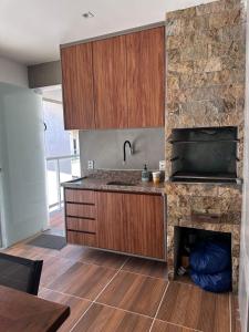 a kitchen with wooden cabinets and a stone wall at Village com 2 suites com ar a 300mts da praia e do rio in Mata de Sao Joao