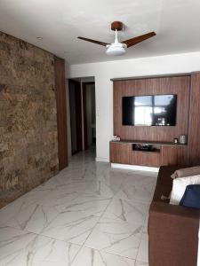 a living room with a couch and a flat screen tv at Village com 2 suites com ar a 300mts da praia e do rio in Mata de Sao Joao