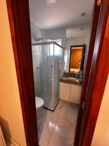 a bathroom with a glass shower and a toilet at Village com 2 suites com ar a 300mts da praia e do rio in Mata de Sao Joao