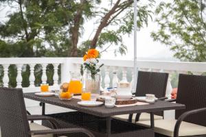 a table with orange juice and a vase of flowers at SaffronStays Chamomile Hills in Kotagiri