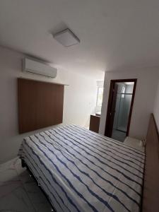 a bedroom with a bed with a blue striped comforter at Village com 2 suites com ar a 300mts da praia e do rio in Mata de Sao Joao