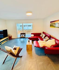 a living room with a red couch and chairs at Brand-New Eiger View 3BR Apartment - Premium Location - Free Parking - Terrace in Grindelwald