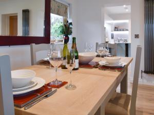 a dining room table with wine bottles and glasses at Mac Shack Cottage - Uk32376 in Ashen