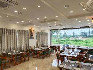 a restaurant with tables and chairs and a large window at Aadhya Hotel & Adhira Restaurant in Orchha