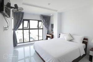 a white bedroom with a bed and a window at Tân Thi Hotel in Quy Nhon
