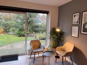 two chairs and a table in a room with a window at Huize Sallandse Stilte in Heeten