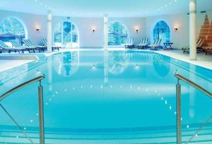 a large swimming pool with blue water in a building at Waldhotel Doldenhorn in Kandersteg +34 photos