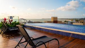 a balcony with two chairs and a swimming pool at Quality Suítes João Pessoa in João Pessoa