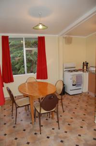 a dining room with a table and chairs and a kitchen at Egmont Eco Leisure Park & Backpackers in New Plymouth