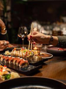a person holding chopsticks over a table with food at Harbour Boutique Hotel in Shëngjin