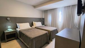 a hotel room with two beds and a television at HDA Miraflores in Termas de Río Hondo