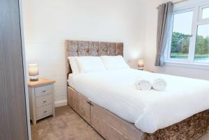 a bedroom with a large bed with two towels on it at Finest Retreats - Silverwood Hideaway Lodge in Errol