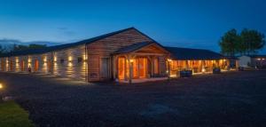 a large wooden barn at night with lights on at Finest Retreats - Silverwood Deluxe Chalet in Errol