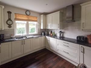 a kitchen with white cabinets and a sink and a window at Cliff Cottage in Port Appin