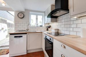 a kitchen with white appliances and a clock on the wall at 4 Bed in Rottingdean oc-bbrott in Rottingdean +4 photos