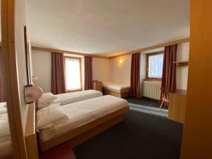 a hotel room with two beds and a desk at Bormiohomes - Case SteLu in Bormio +87 photos