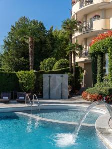 a swimming pool with a fountain in front of a building at Villa e Palazzo Aminta - A Leading Hotel of The World in Stresa