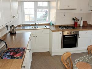 a kitchen with white cabinets and a stove top oven at Sunnyside in Sandsend