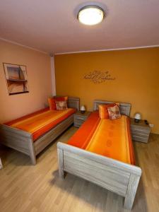 two beds with orange sheets in a room at Ferienwohnung ILSENHOF in Königsbrück