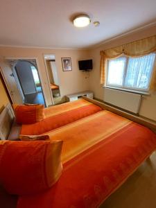 a bedroom with three beds with orange sheets at Ferienwohnung ILSENHOF in Königsbrück