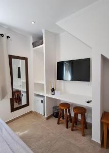 a room with a desk with two stools and a mirror at Pousada Fenícia in Japaratinga