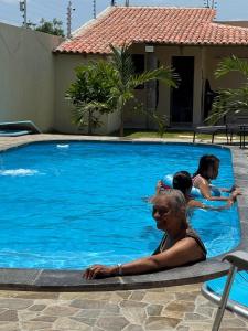 a woman and two children swimming in a swimming pool at Espaço Recanto Del Mar in Paracuru