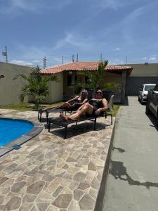 two women sitting on benches next to a pool at Espaço Recanto Del Mar in Paracuru +11 photos