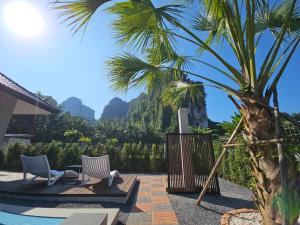 a patio with two chairs and a palm tree at The white mountain pool villa Ao Nang in Ban Thai Thai