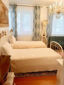 two beds in a room with curtains and a chandelier at Bed and Breakfast in Old Town in Naujoji Akmenė