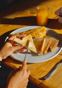a person holding a plate with toast and eggs at Hotel Sol y Mar in Santa Catalina
