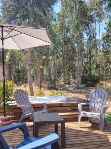 two chairs and a table with an umbrella on a deck at Cabaña Matanzas tinaja privada vista al bosque in Boca Pupuya