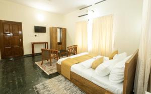 a bedroom with a bed and a table and a television at Bloom Fort Villa in Kannur