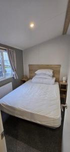 a bedroom with a bed with white sheets and pillows at 8 berth 3 Bedroomed CARAVAN Lyons Robin Hood Rhyl 17 Elm Crescent in Meliden +24 photos