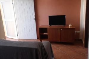 a bedroom with a television on a dresser and a door at Maio Sweet Tartaruga in Vila do Porto