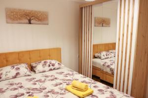 a bedroom with a bed with a yellow towel on it at Apartman Wish Lux in Vrnjci