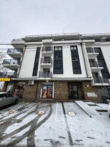 a large building with snow on the ground in front of it at Apartman Wish Lux in Vrnjci