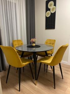 a dining room with a table and yellow chairs at Golden corner in Plungė