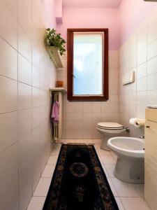 a bathroom with a toilet and a window and a rug at Dimora Marisa in Albiate +39 photos