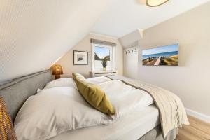 a bedroom with a bed with white sheets and yellow pillows at Mare in Hörnum