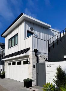 a white house with a white garage at 2026 Award Winner, Luxe 2BR, steps to sand & pier, with fire pit, AC and parking in Newport Beach +25 photos
