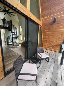 a screened porch with two chairs and a staircase at Post Oak Perch-Cozy Forest A-frame Near Bentonville in Rogers