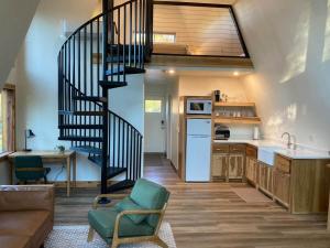 a kitchen with a spiral staircase in a living room at Dogwood Den- Cozy Forest A-Frame Near Bentonville in Rogers
