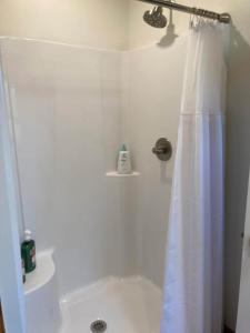 a bathroom with a shower with a white shower curtain at Dogwood Den- Cozy Forest A-Frame Near Bentonville in Rogers