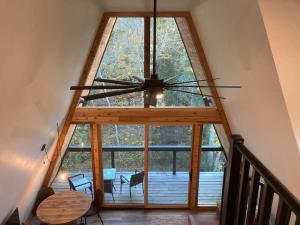 a large window in a room with a ceiling fan at Dogwood Den- Cozy Forest A-Frame Near Bentonville in Rogers
