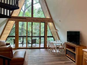 a living room with a table and a large window at Black Gum Getaway-Cozy Forest A-frame Near Bentonville in Rogers